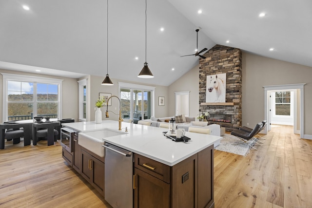 kitchen with pendant lighting, a fireplace, dishwasher, sink, and a kitchen island with sink