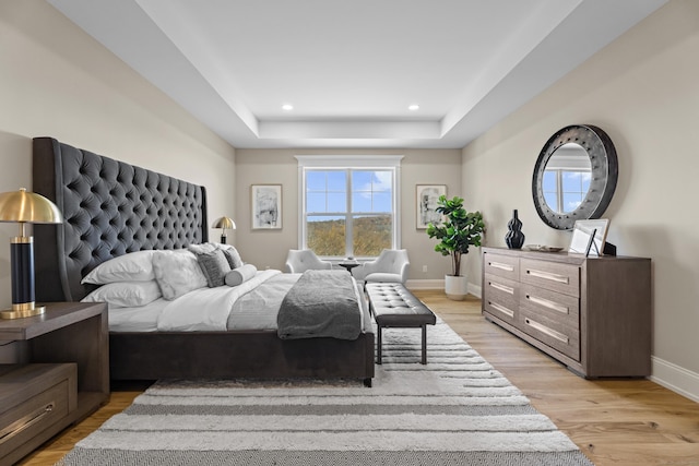 bedroom with a tray ceiling and light hardwood / wood-style floors