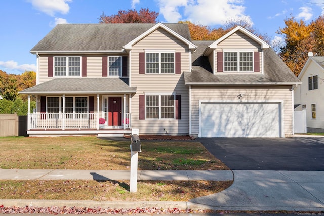 view of front of house with a porch, a front yard, and a garage