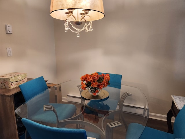 dining area featuring dark wood-type flooring, a baseboard heating unit, and an inviting chandelier