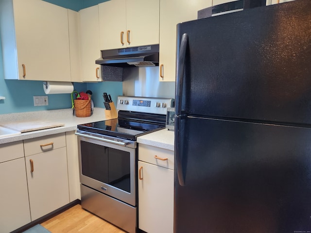 kitchen featuring black refrigerator, stainless steel range with electric stovetop, and light wood-type flooring