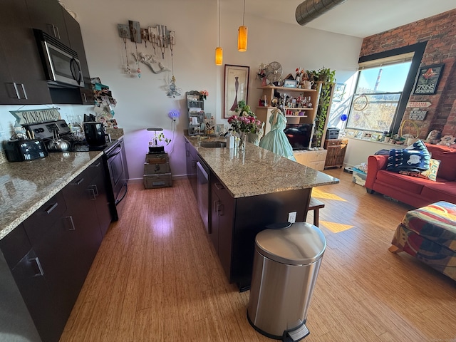 kitchen featuring appliances with stainless steel finishes, light stone countertops, pendant lighting, light hardwood / wood-style floors, and a center island