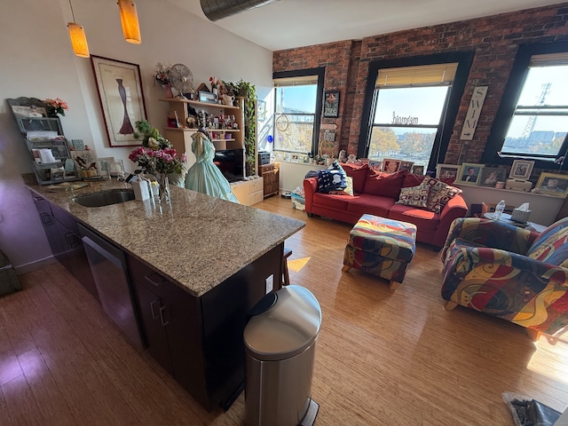 living room with brick wall, sink, and light hardwood / wood-style flooring