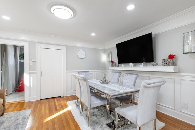 dining space with crown molding and light hardwood / wood-style flooring