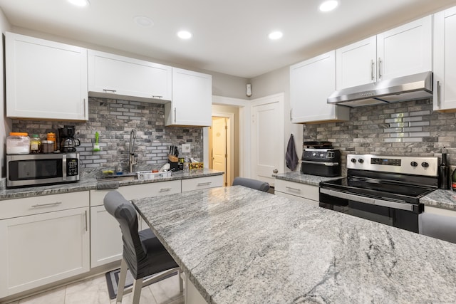 kitchen with white cabinetry, light stone counters, appliances with stainless steel finishes, and decorative backsplash