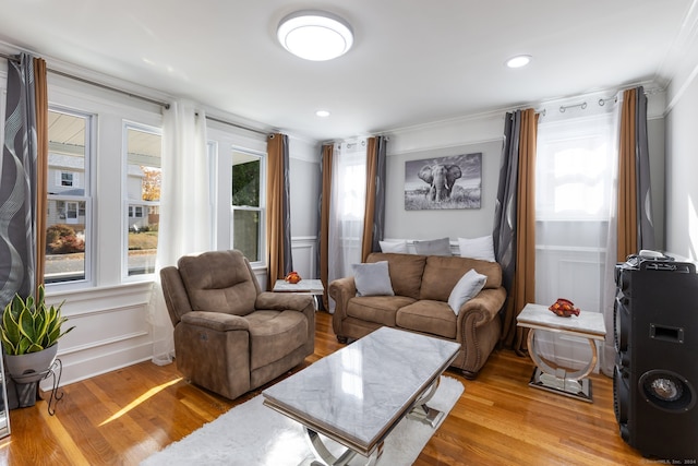 living room with a wealth of natural light, crown molding, and light hardwood / wood-style floors