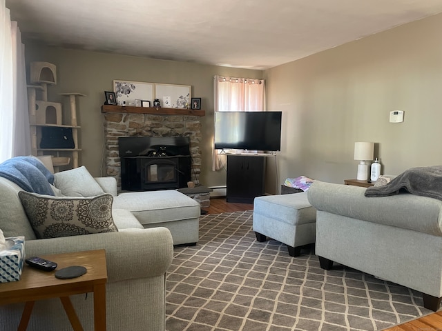 living room with a baseboard heating unit, a wood stove, and dark wood-type flooring