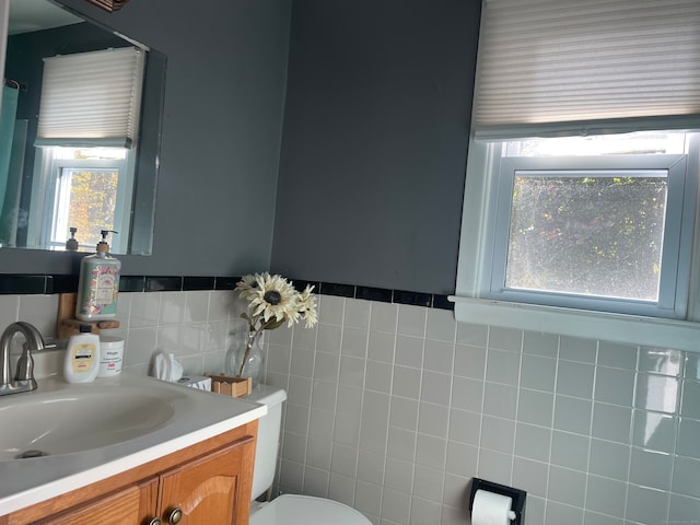 bathroom with vanity, toilet, and tile walls