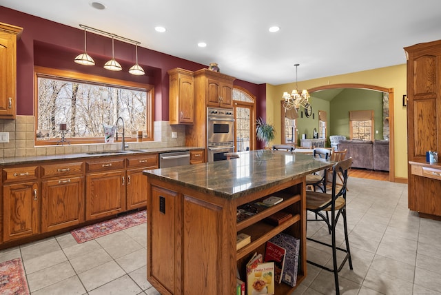 18 Eastern Ln, New Milford, CT 06776 - kitchen featuring appliances with stainless steel finishes, a chandelier, brown cabinetry, a kitchen island, and tasteful backsplash