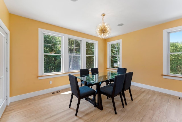 dining area with a chandelier, light wood-type flooring, visible vents, and baseboards