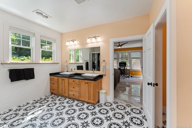 ensuite bathroom featuring double vanity, a sink, visible vents, and tile patterned floors