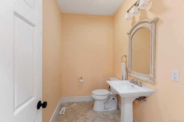 half bath with tile patterned flooring, baseboards, visible vents, and toilet