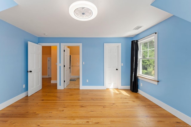 unfurnished bedroom featuring light wood-type flooring, visible vents, and baseboards