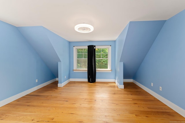 bonus room featuring vaulted ceiling, light wood-style flooring, and baseboards