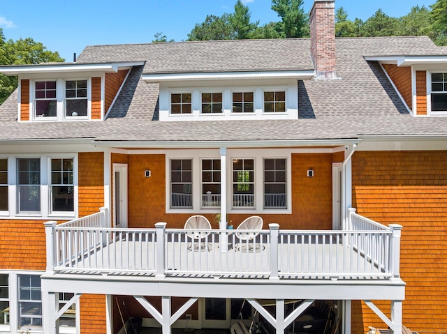 view of front of home featuring a shingled roof, a chimney, and a balcony