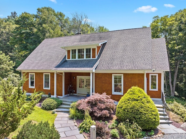 view of front facade with a shingled roof and french doors