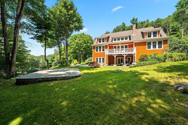 rear view of house featuring a patio area, a lawn, a chimney, and a wooden deck