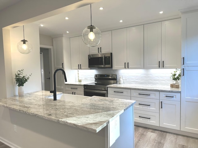 kitchen featuring light stone counters, white cabinets, decorative light fixtures, and appliances with stainless steel finishes