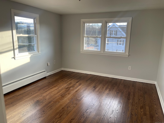 spare room with a baseboard radiator, a wealth of natural light, and dark wood-type flooring