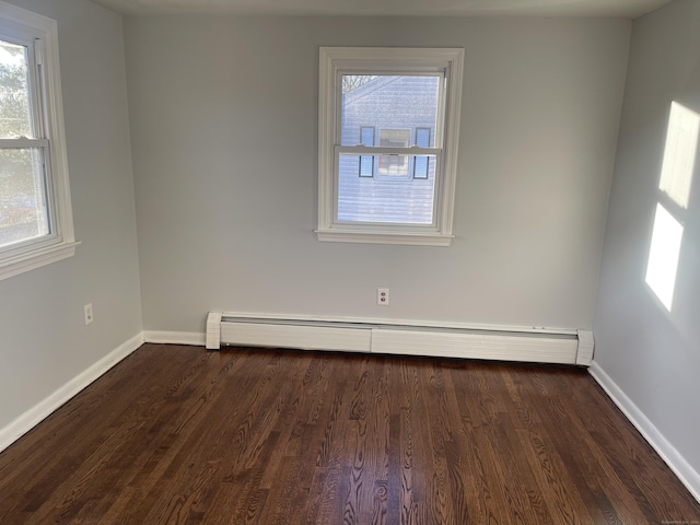 unfurnished room featuring dark wood-type flooring, a wealth of natural light, and a baseboard heating unit