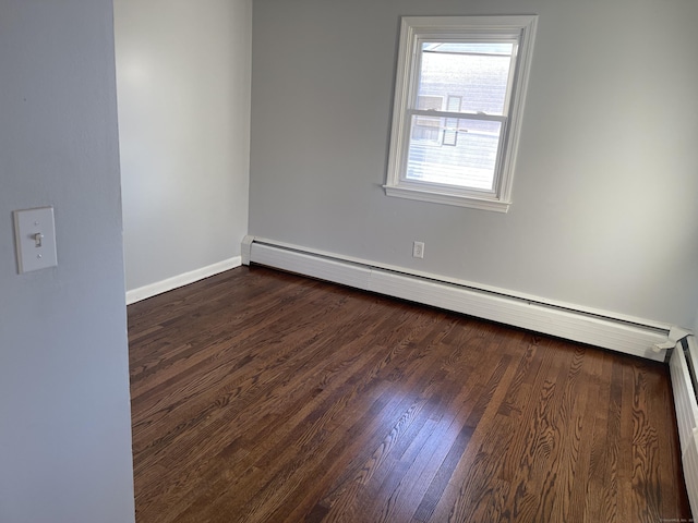 empty room featuring baseboard heating and dark hardwood / wood-style floors