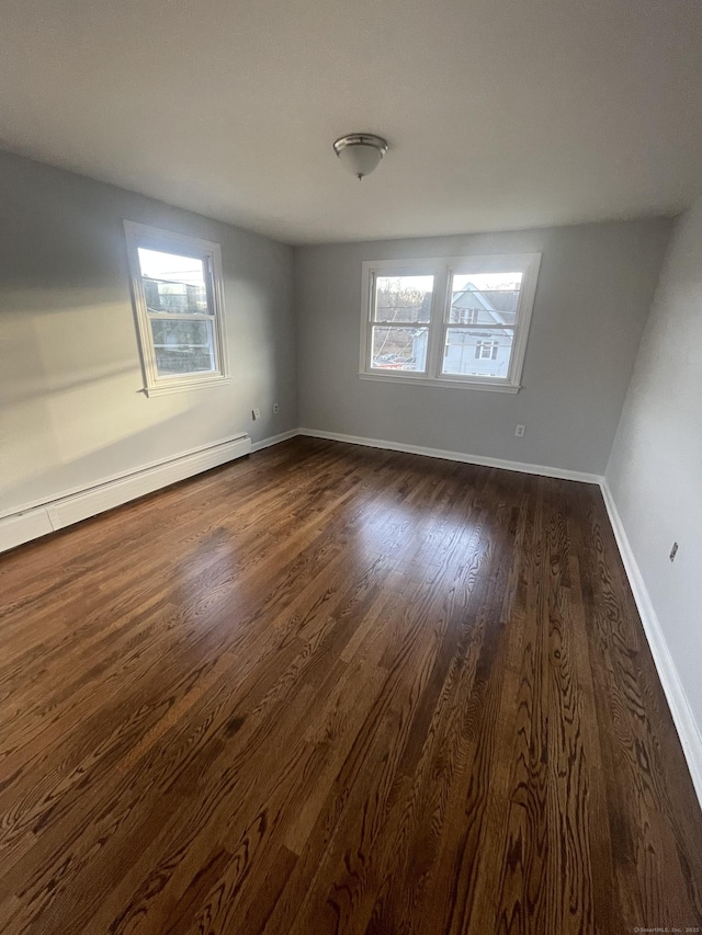 spare room with dark hardwood / wood-style flooring and a baseboard heating unit