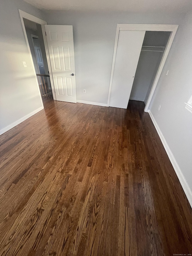 unfurnished bedroom featuring dark hardwood / wood-style flooring and a closet