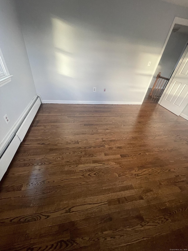 unfurnished room with dark hardwood / wood-style flooring and a baseboard radiator