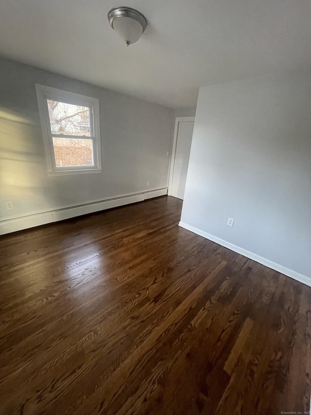 spare room featuring dark hardwood / wood-style flooring and a baseboard heating unit