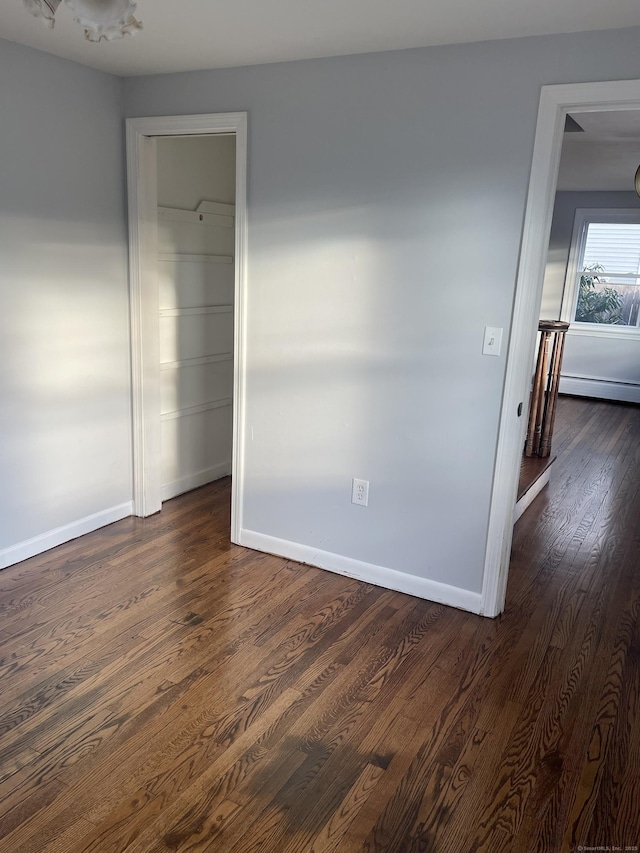 empty room featuring dark hardwood / wood-style floors and baseboard heating