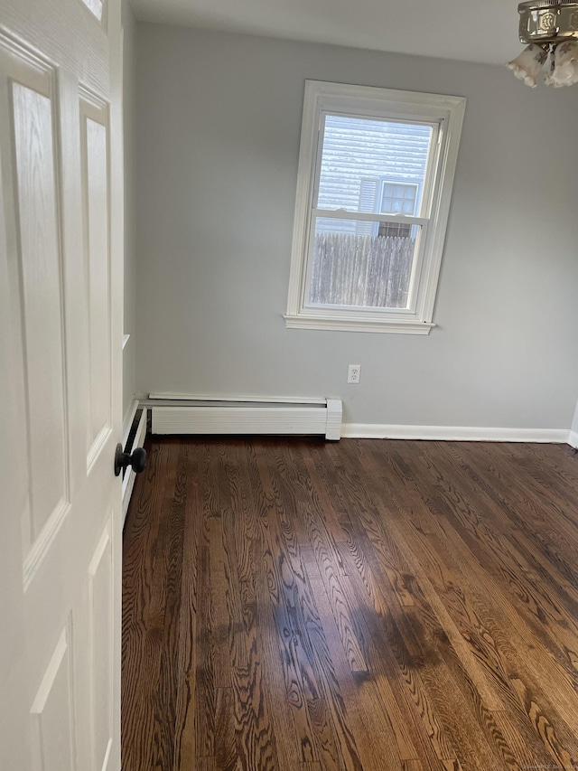 spare room featuring baseboard heating and dark wood-type flooring