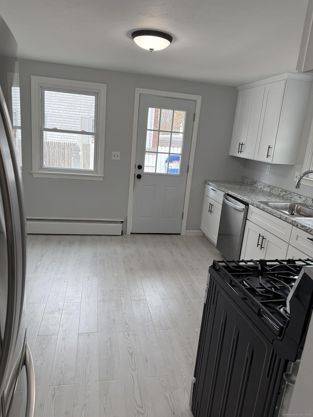 kitchen featuring sink, white cabinets, a baseboard heating unit, and appliances with stainless steel finishes