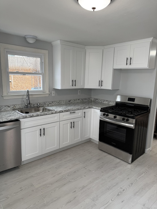 kitchen with sink, white cabinets, stainless steel appliances, and light hardwood / wood-style floors