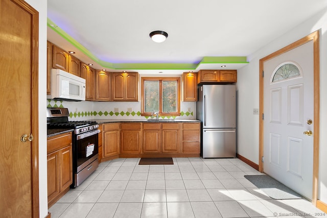 kitchen featuring stainless steel appliances, decorative backsplash, sink, and light tile patterned flooring