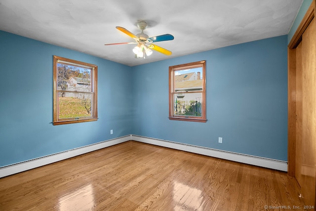 spare room featuring light hardwood / wood-style floors, a baseboard heating unit, ceiling fan, and a wealth of natural light