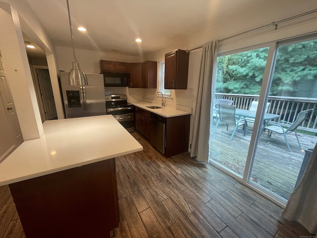 kitchen with a kitchen island, dark hardwood / wood-style flooring, stainless steel appliances, pendant lighting, and decorative backsplash