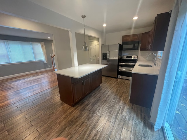 kitchen with sink, a center island, pendant lighting, appliances with stainless steel finishes, and dark hardwood / wood-style flooring