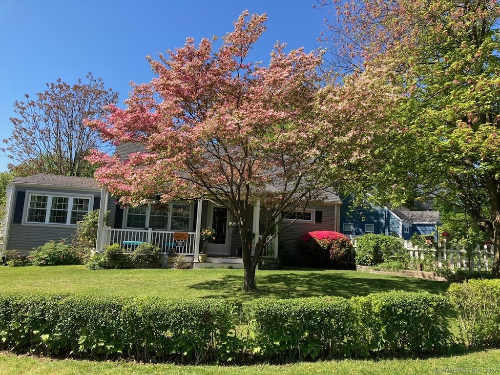 obstructed view of property with a porch and a front lawn