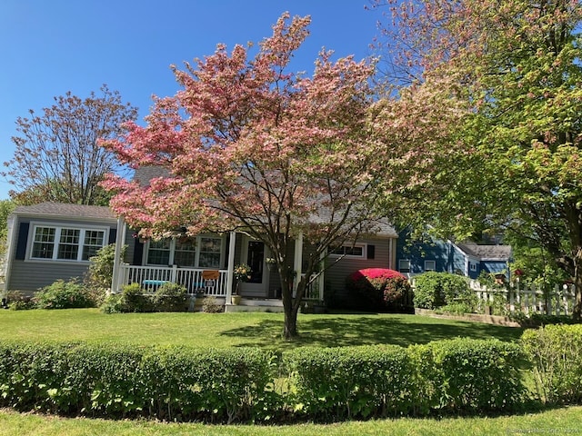 obstructed view of property with a porch and a front lawn