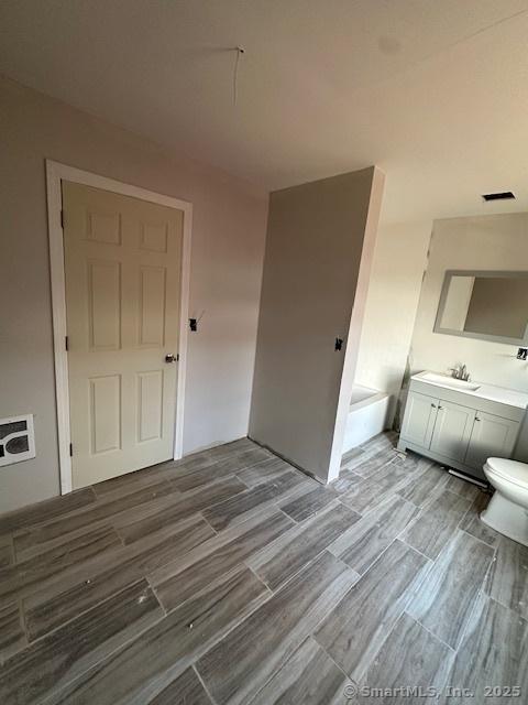 bathroom with vanity, a bath, and toilet