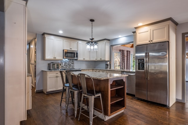 kitchen with a kitchen island, dark wood-type flooring, hanging light fixtures, stainless steel appliances, and light stone counters