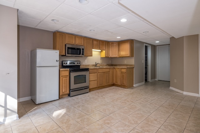 kitchen featuring light tile patterned floors, appliances with stainless steel finishes, sink, and a drop ceiling