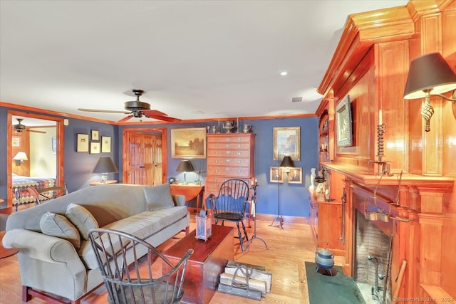 living room with light hardwood / wood-style flooring, ornamental molding, and ceiling fan