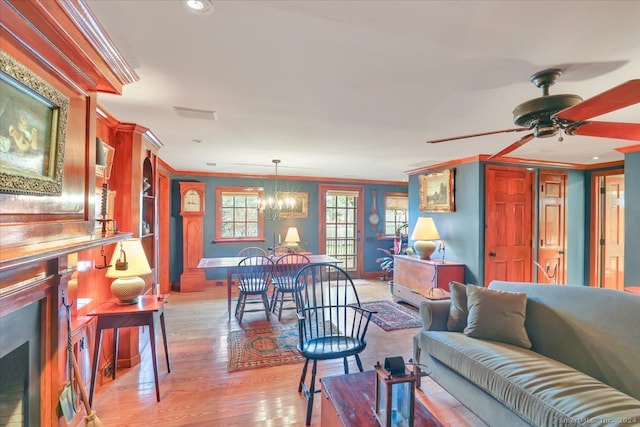 living room with crown molding, ceiling fan with notable chandelier, and light hardwood / wood-style floors