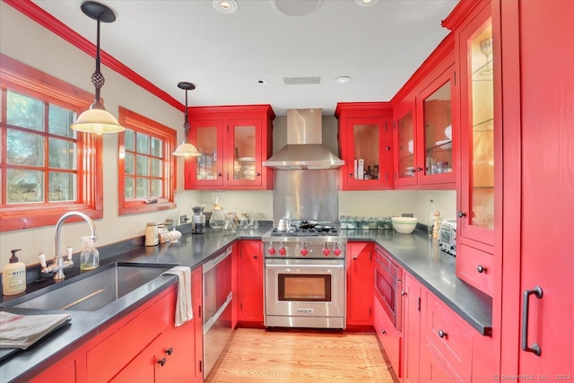 kitchen featuring wall chimney exhaust hood, stainless steel appliances, sink, pendant lighting, and light wood-type flooring