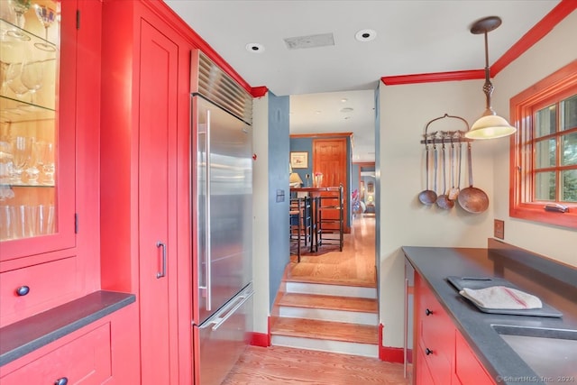 kitchen with sink, light hardwood / wood-style floors, decorative light fixtures, and stainless steel built in refrigerator