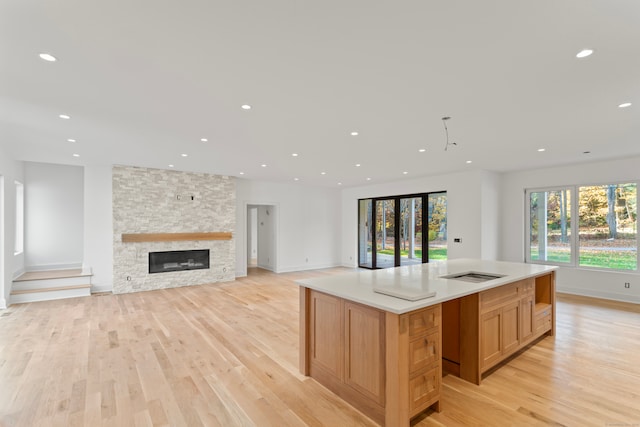 kitchen featuring a stone fireplace, a center island, and light hardwood / wood-style flooring