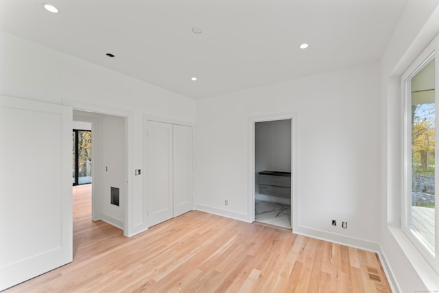 unfurnished bedroom featuring connected bathroom, light hardwood / wood-style floors, and a closet