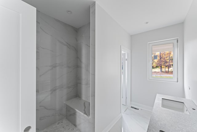 bathroom with vanity and a tile shower