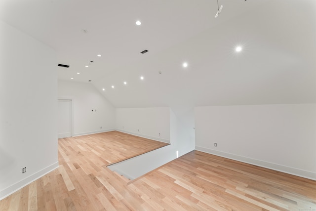 additional living space with light hardwood / wood-style floors and vaulted ceiling